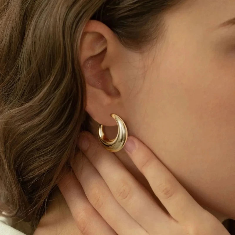 Close-up of a woman wearing stylish gold crescent hoop earrings