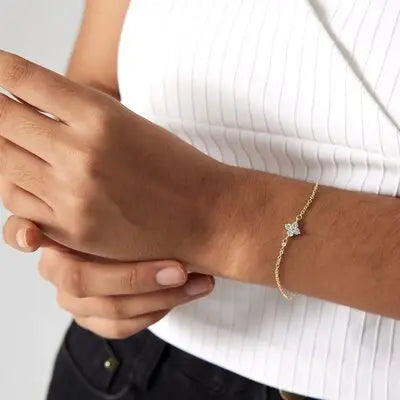 Woman wearing a gold butterfly bracelet with a white sleeveless top.