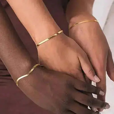 Three people wearing gold minimalist bracelets, close-up on hands.