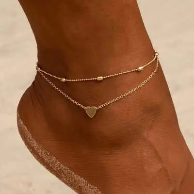 Delicate anklets with beads and heart pendant, highlighting women's ankle jewelry.