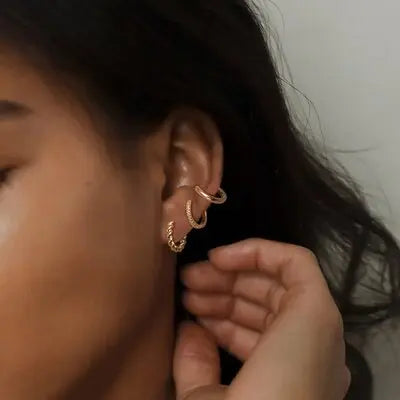 women with 3 gold hoop earrings