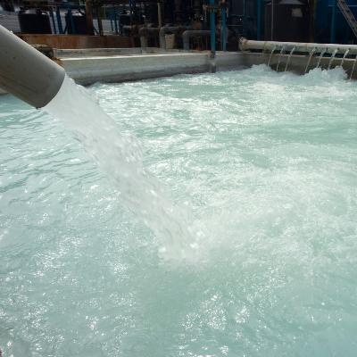 Water being poured into a large tank in a treatment facility.