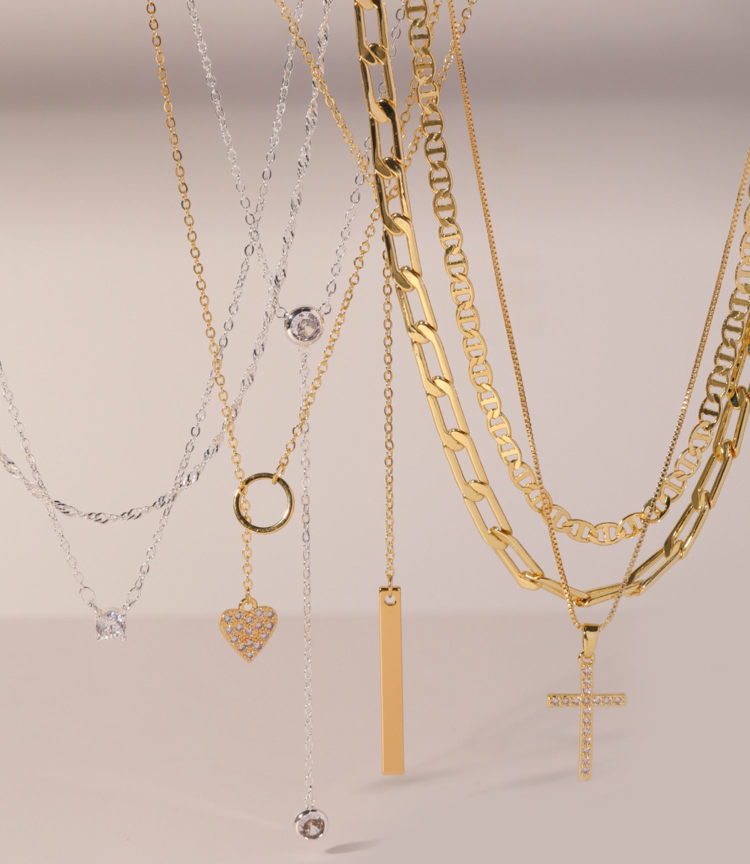 Assorted gold and silver necklaces with various pendants displayed on a light background.