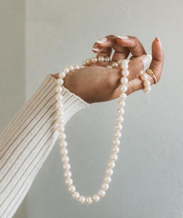 Hand holding a pearl necklace.